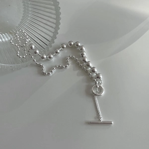 Detail of S925 sterling silver T-bar clasp and round bead chain on a white surface