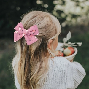 Pink floral bow hair clip with embroidery on golden hair, outdoor lifestyle view