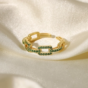 Detail of 18k gold plated adjustable ring with green crystals on white silk