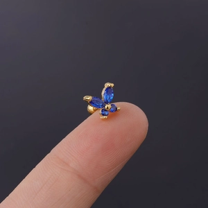 Macro shot of tiny blue zircon butterfly earring with secure screw back on a finger