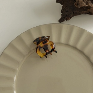 Macro detail of tortoiseshell acetate claw clip on a ceramic plate with natural decor