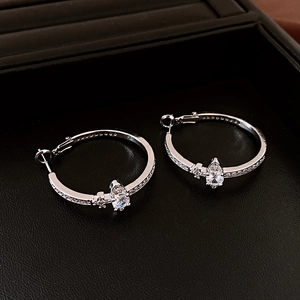 Detailed view of silver hoop earrings with shimmering zircons and teardrop pendant