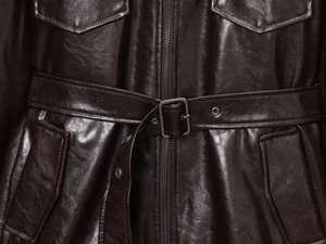 Detailed macro view of dark brown leather jacket featuring belt buckle and zip pockets