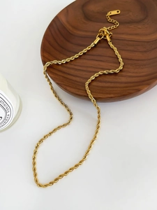 Détail d'un collier chaîne torsadée en titane plaqué or 18 carats avec fermoir mousqueton
