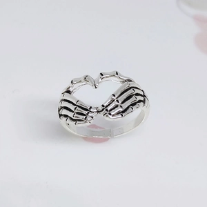 Retro antique silver skeleton hand heart ring in gothic punk style with minimalist white background