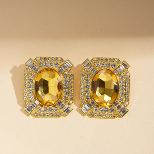 Detail of vintage gold earrings with yellow oval gemstone and sparkling crystal borders