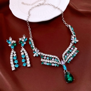 Macro view of vintage silver necklace and earrings set with green crystals on silk