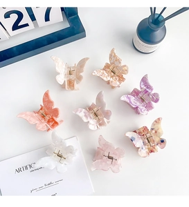 Flat lay of eight colorful acetate butterfly hair claws with marble textures and metal springs