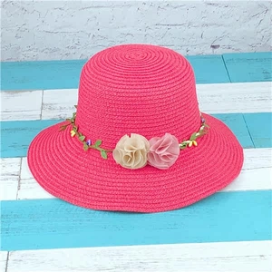 Detail of rose red straw sun hat featuring decorative floral vine and woven texture