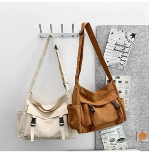 Détail de sacs bandoulière en toile beige et marron suspendus dans un décor de bureau