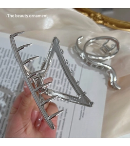 Detailed close-up of large silver metal hair claw with geometric triangle hollow design