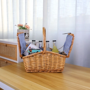 Handwoven willow picnic basket with double lids and blue gingham lining on wood table