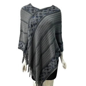 Detail shot of grey knitted shawl with blue diamond patterns and fringe hem on mannequin