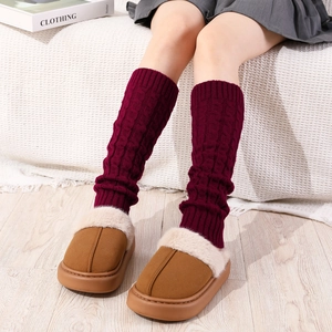 Detail of burgundy cable knit leg warmers paired with plush faux fur slippers