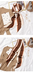 Detailed view of a brown and orange striped silk scarf tied on a stylish handbag