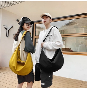 Street style shot of models carrying large yellow and black oxford cloth crossbody bags