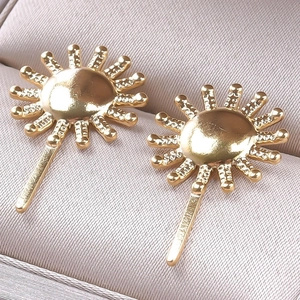 Detail of golden sunburst hairpins with beaded texture on a beige velvet jewelry box