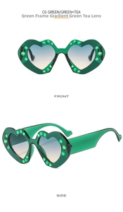 Detail view of heart-shaped sunglasses with green rhinestones and gradient tea lenses