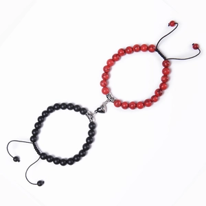 Close-up of heart-shaped magnetic clasp on red and black beaded couple bracelets