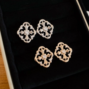 Detail of gothic silver and gold diamond cross earrings on black velvet background