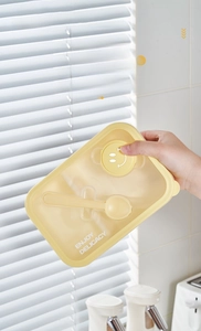 Detail of yellow bento box lid with built-in spoon storage and secure sealing ring