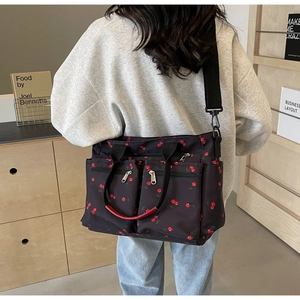 Detail of black nylon tote bag with cherry print showing large capacity and zipper pockets