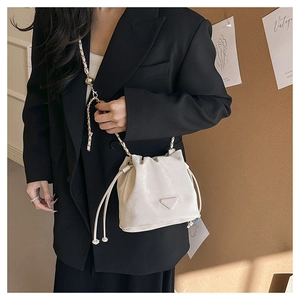 Detail of white drawstring bucket bag with gold chain strap on model with vintage aesthetic