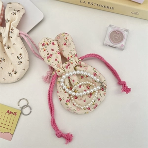 Close-up of pearl necklaces with a floral bunny-ear drawstring storage pouch