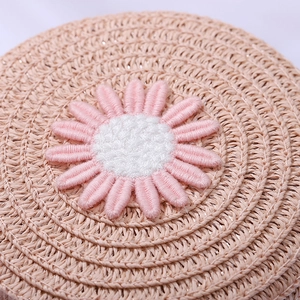 Detailed macro view of woven straw texture with daisy embroidery and shiny metallic threads