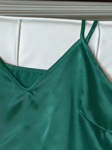 Détail d'un caraco en satin de soie vert foncé avec de fines bretelles et un col en V