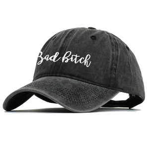 Close-up of white script embroidery on a washed black cotton vintage baseball cap