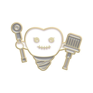 Detail of a cartoon tooth implant enamel pin with cute expression and gold plating
