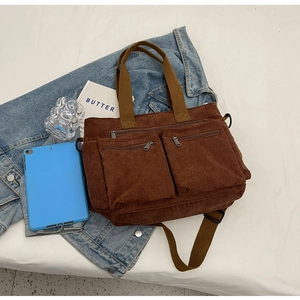 Brown corduroy tote bag detail with double zipper pockets on denim jacket backdrop