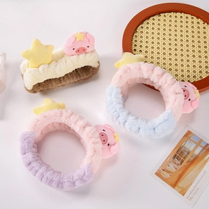Bandeau en peluche cochon aux couleurs pastel sur un plateau en rotin pour le visage