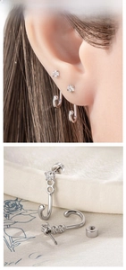 Detail of silver cat tail earring with zircon stud and spiral back on floral paper