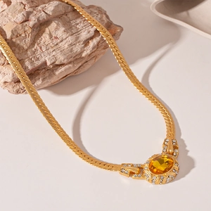 Detail of vintage gold snake chain featuring a yellow oval gemstone with rhinestone trim