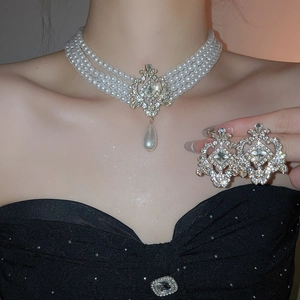 Détail d'une parure élégante en perles et strass portée par un mannequin en robe noire