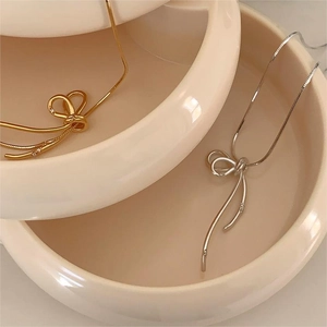 Detail of minimalist S925 sterling silver bow necklaces in gold and silver finishes