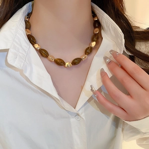 Detail of a brown resin oval geometric necklace worn by a model for a chic daily look