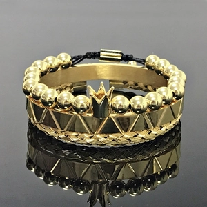 Detailed close-up of gold crown bead bracelet and textured geometric cuff on black surface