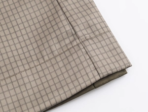 Detailed close-up of light beige plaid pattern fabric with precise stitching lines