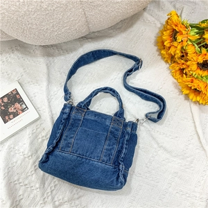 Blue denim tote bag with adjustable strap and front pocket on a casual set