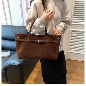 Brown suede tote bag with decorative buckle shown in a modern home interior setting