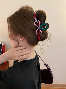 Détail d'une pince à cheveux chic en forme de nœud rouge et rose sur cheveux ondulés