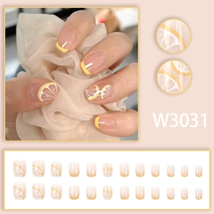 Detail view of lemon themed press-on nails with yellow French tips and fruit art
