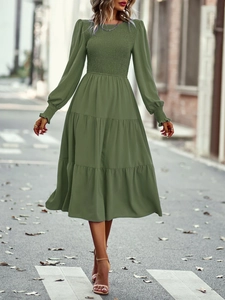 Détail de robe longue verte à manches longues avec buste froncé et jupe à volants