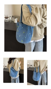Nahaufnahme der blauen Denim-Beuteltasche mit gelber Blumenstickerei und Schultergurt