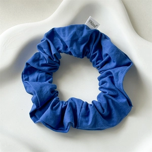 Detailed close-up of blue cotton scrunchie texture with FMdrea brand tag on white tray
