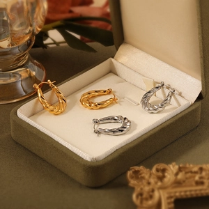Chic twisted croissant hoop earrings in gold and silver finish displayed in a velvet box