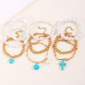 Detail of bohemian gold bracelets with turquoise star charms and pearl beads